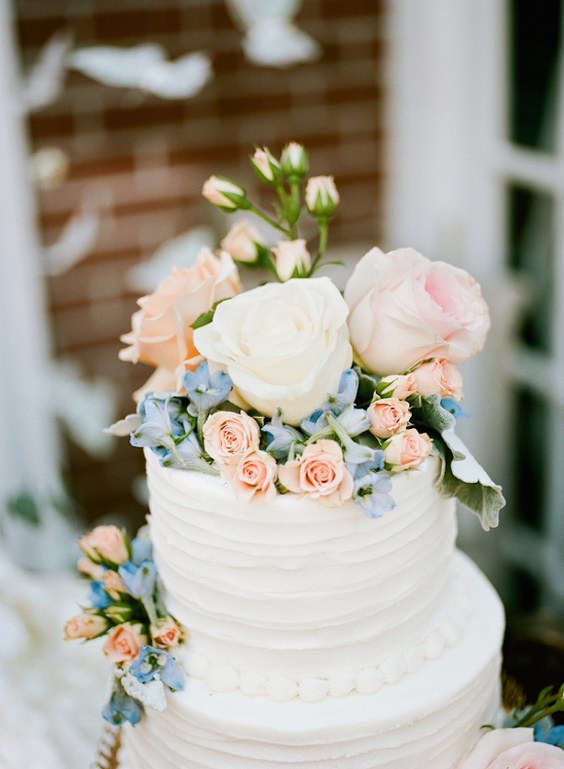 white wedding cake with dusty blue and blush florals for march wedding colors 2022 dusty blue white and blush