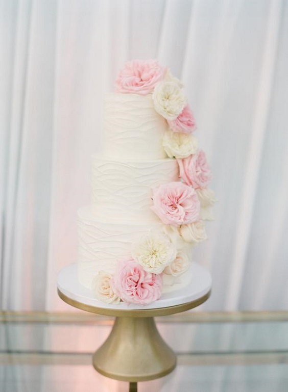 wedding cake dotted with light pink and pale yellow flowers for April wedding colors 2022 light pink pale yellow and gold colors