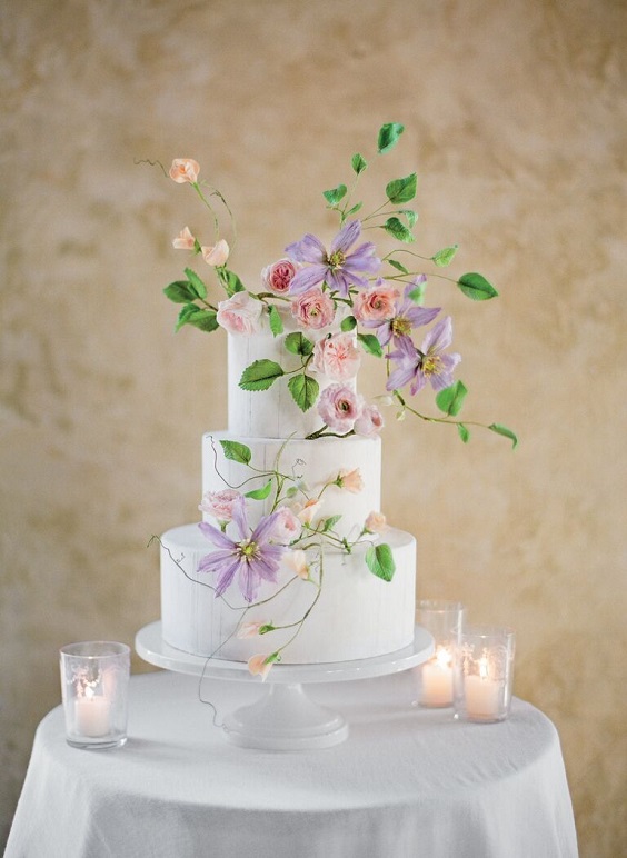 wedding cake dotted with lavender flowers and greenery for April wedding colors 2022 light pink pale yellow and gold colors