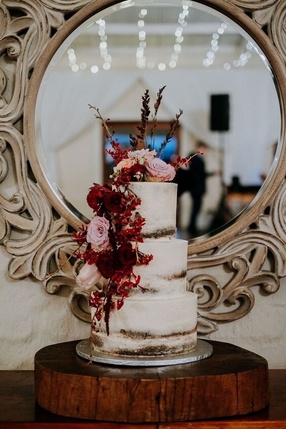 white wedding cake with burgundy flowers for fall wedding colors 2022 burgundy and blush