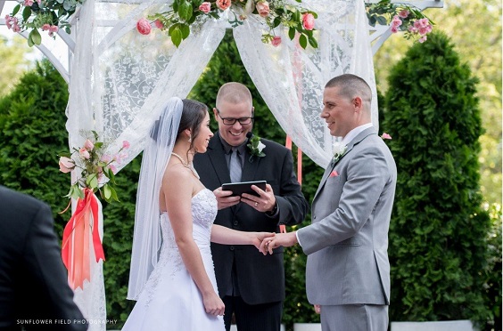 wedding arch decorated with coral flowers and greenery for summer wedding color 2022 coral and grey colors