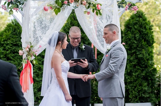 wedding arch decorated with coral flowers and greenery for summer wedding color 2022 coral and grey colors