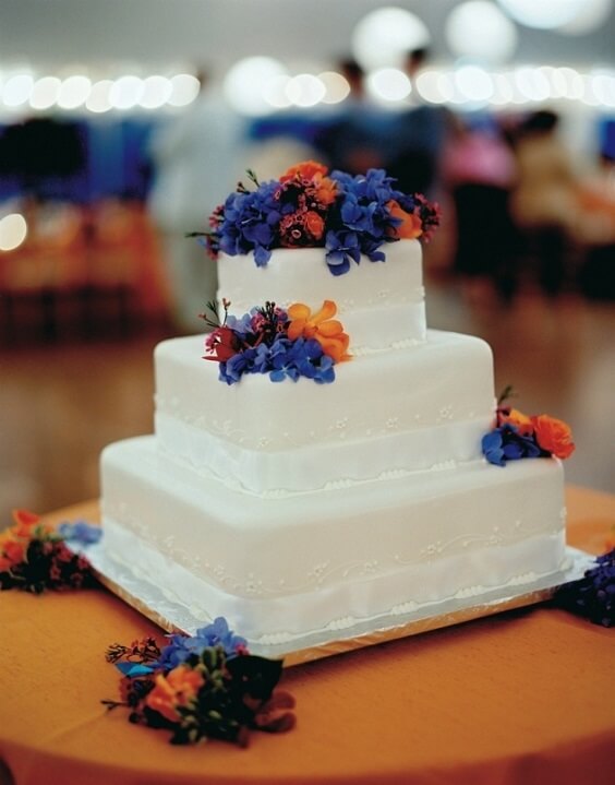 wedding cake with dark blue and orange flowers for winter wedding colors 2022 dark blue and orange