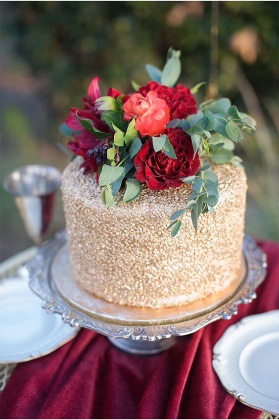 small gold wedding cake with red flowers and greenery for winter wedding colors 2022 red and gold