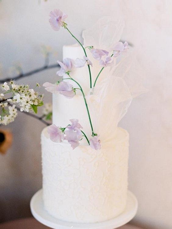 white wedding cake dotted with purple flower for spring wedding color palettes yellow pink purple colors