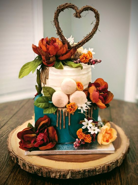 teal and white wedding cake dotted with red and orange flowers for fall wedding colors 2023 teal and orange