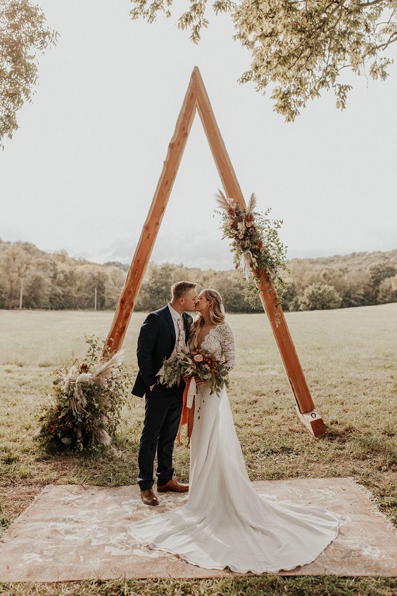 triangle wedding arbor with rug and floral installation for sage green wedding colors 2023 sage green and terracotta