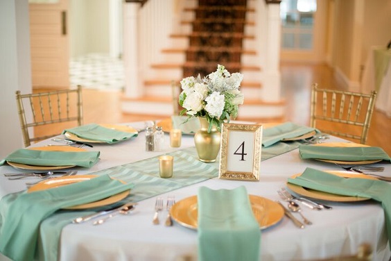 ivory table linens with a striped sage green runner and gold charger plates for sage green wedding colors 2023 sage green and gold