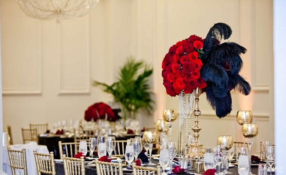 red roses and black feather centerpiece gold vases and cups for red and black wedding colors red black and gold