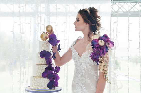 wedding cake dotted with purple flower and gold apples for purple wedding colors 2023 purple and gold