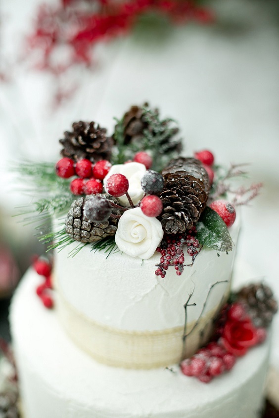 white wedding cake with red berries and pineal cones for winter wedding colors 2023 red green and white