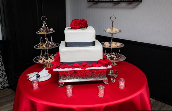 red wedding tablecloth and white wedding cake with black sash and red flowers decorations for red wedding colors 2023 red and black
