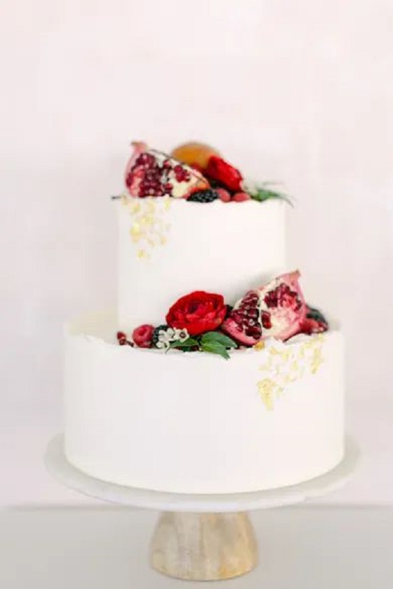 white wedding cake dotted with red roses and gold cream for red wedding colors 2023 red gold and white