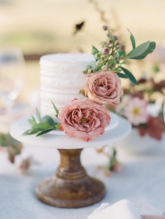 white wedding cake dotted with dusty rose flower and sage greenery for august wedding colors 2023 dusty rose and sage