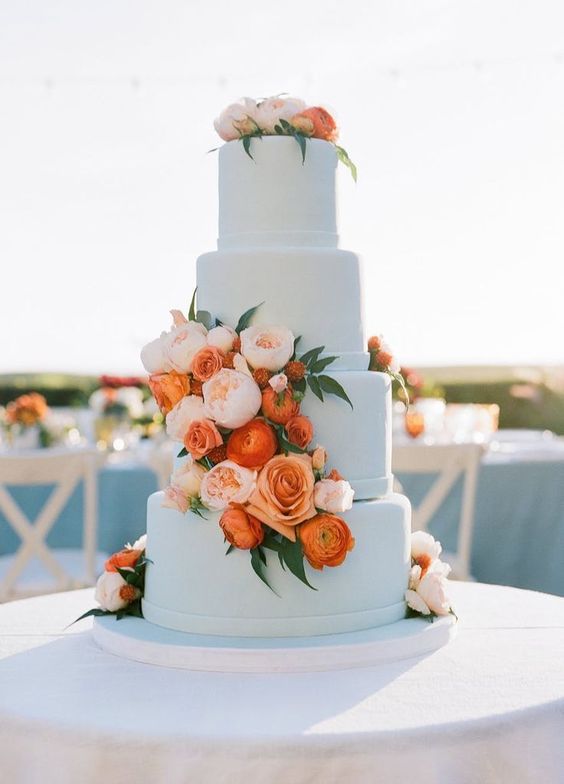 white wedding cake dotted with coral and light pink flowers for august wedding colors 2023 light blue coral and peach