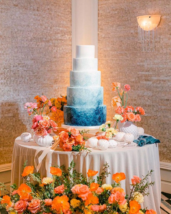 white and blue wedding cake decorated with orange flowers for august wedding colors 2023 orange and royal blue