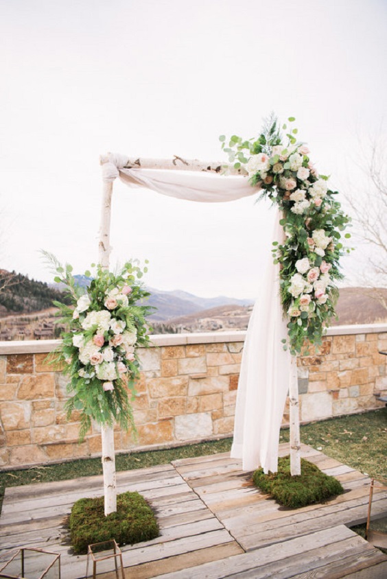 white and light pink flower decorated wedding arch for blue wedding colors 2023 dusty blue and light pink