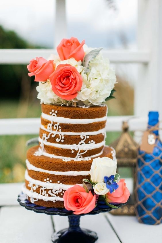 wedding cake dotted with coral and white flowers for blue wedding colors 2023 royal blue and coral