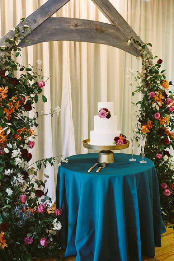 wedding arch decorated with burgundy pink and orange flowers for blue wedding colors 2023 teal blue burgundy and orange