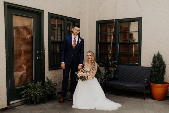 bridegroom in navy suit and a terro cotta tie for november wedding colors 2023 rust and terro cotta