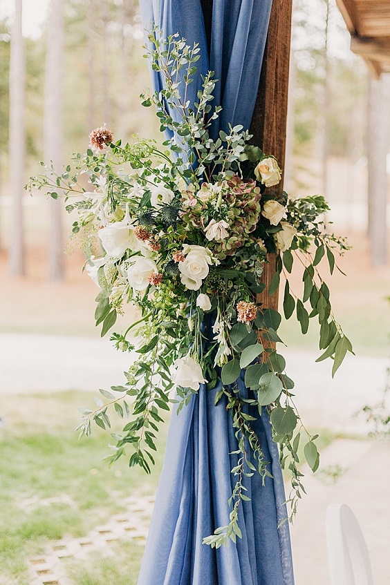 light blue cloth white flower and greenery decorated wedding arch for november wedding colors 2023 shades of blue