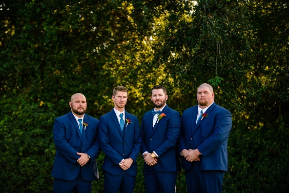 groomsmen in navy blue suits teal ties and orange flower corsage for november wedding colors 2023 teal red and orange
