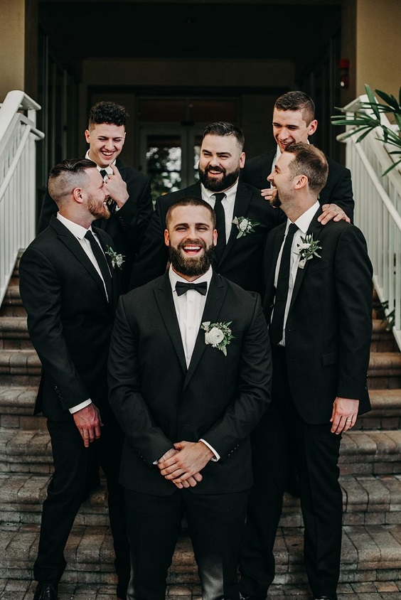 black groomsmen suits with white flower and sage greenery corsage for green wedding theme 2023 sage green colors