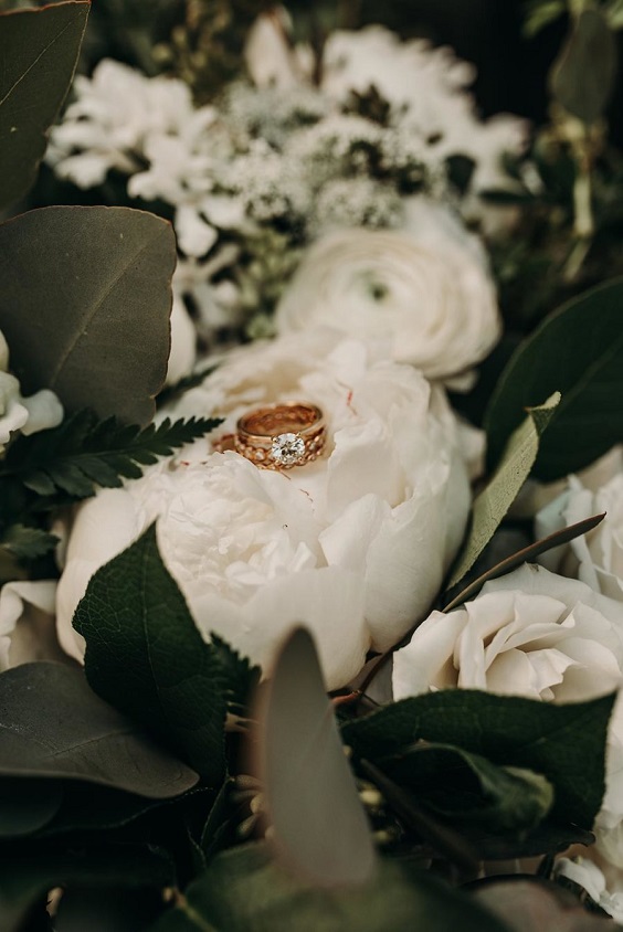 wedding rings hidden in white flower and sage greenery for green wedding theme 2023 sage green colors