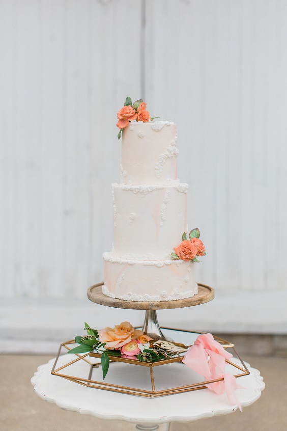 white wedding cake dotted with peach flowers for april wedding color schemes for 2023 sage and peach