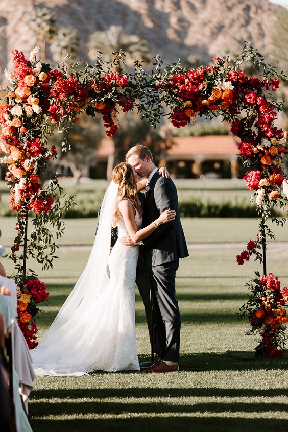 red and shades of pink flowers and greenery wedding arch for april wedding color schemes for 2023 shades of pink and red