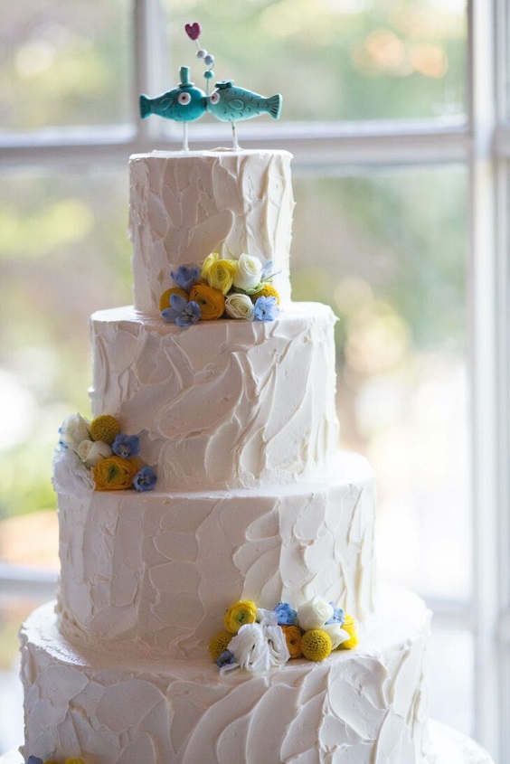 white buttercream wedding cake with kissing fish topper navy and yellow florals for yellow weddding themes for 2023 yellow and navy