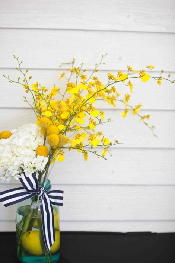 yellow and white flowers in jar with navy striped ribbons for yellow weddding themes for 2023 yellow and navy