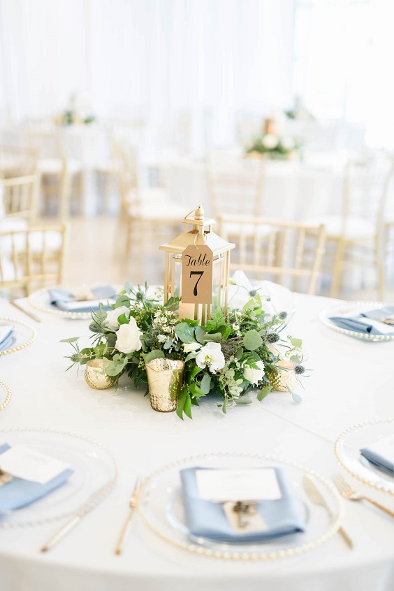 wedding table centerpieces with flowers and gold cups and table number card for dusty blue wedding themes for 2023 dusty blue and gold