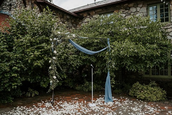 wedding arch decorated with white flower dusty blue cloth and green leaves for dusty blue wedding themes for 2023 dusty blue green and white