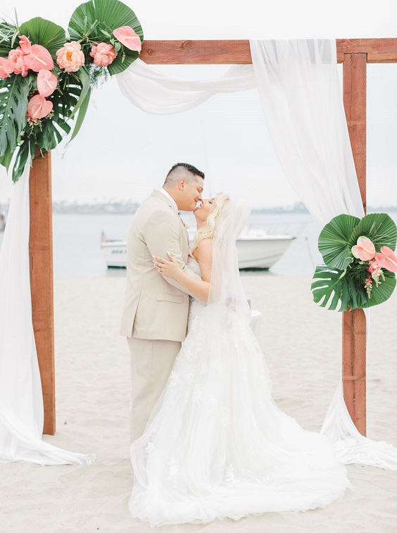 wedding arch decorated with pink flowers and green tropical leaves for great summer wedding color palettes for 2024 gold hot pink and green