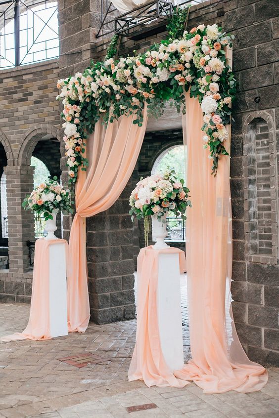 peach wedding arch decorated with white flowers and greenery for great summer wedding color palettes for 2024 peach white and green
