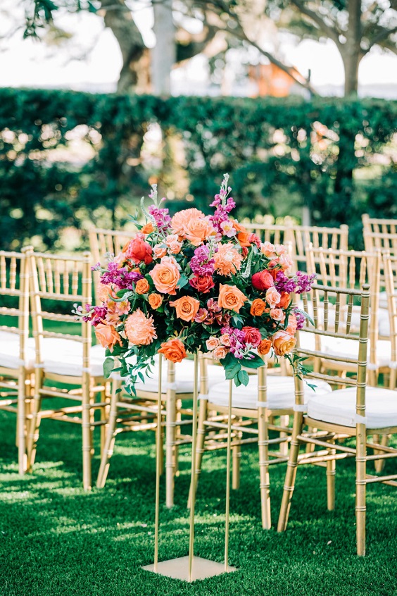 wedding aisle decorated with fuschia and orange flowers and greenery for great summer wedding color palettes for 2024 sage orange and fuschia