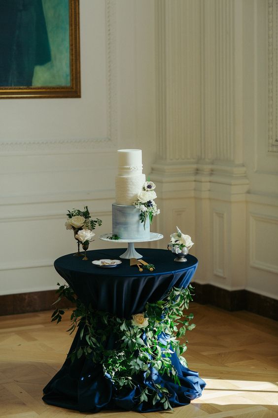 white and blue wedding cake in a wedding table covered with navy blue cloth for emerald green wedding color schemes for 2024 emerald green and navy blue
