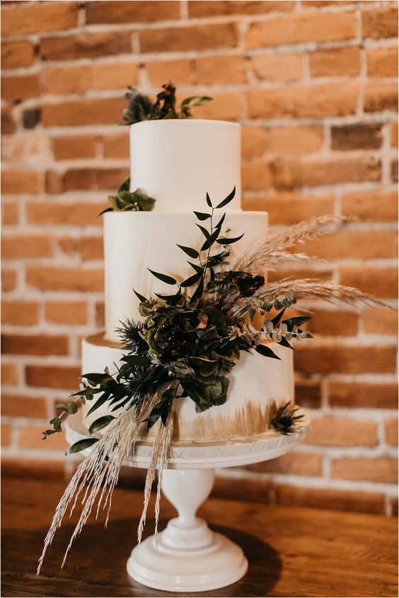 white and champagne wedding cake dotted with greenery for emerald green wedding color schemes for 2024 emerald green and champagne