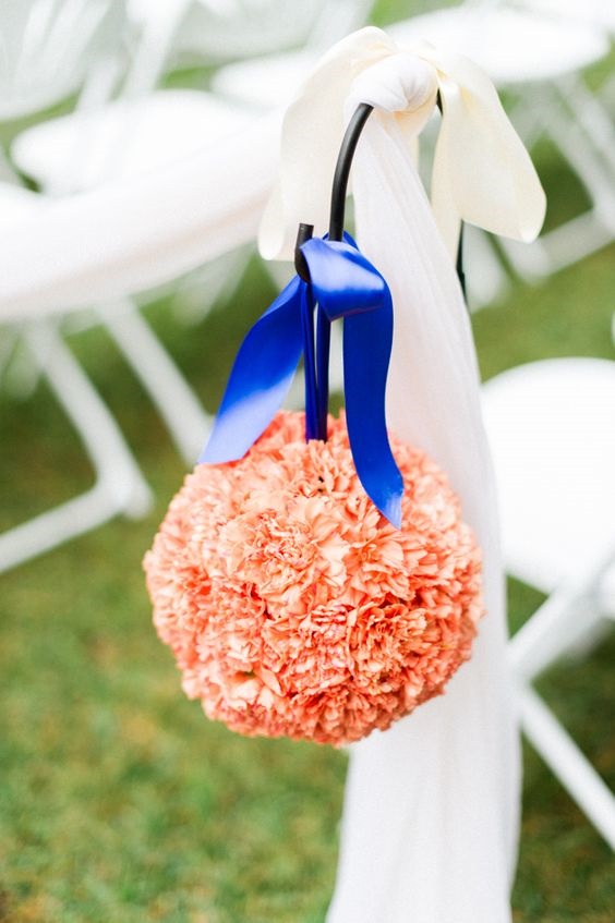 coral flower ball with royal blue ribbons as wedding aisle chair decorations for royal blue wedding colors 2024 royal blue and coral
