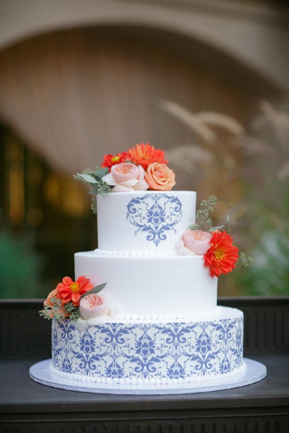 white and blue floral wedding cake dotted with coral and light pink flowers for royal blue wedding colors 2024 royal blue and coral