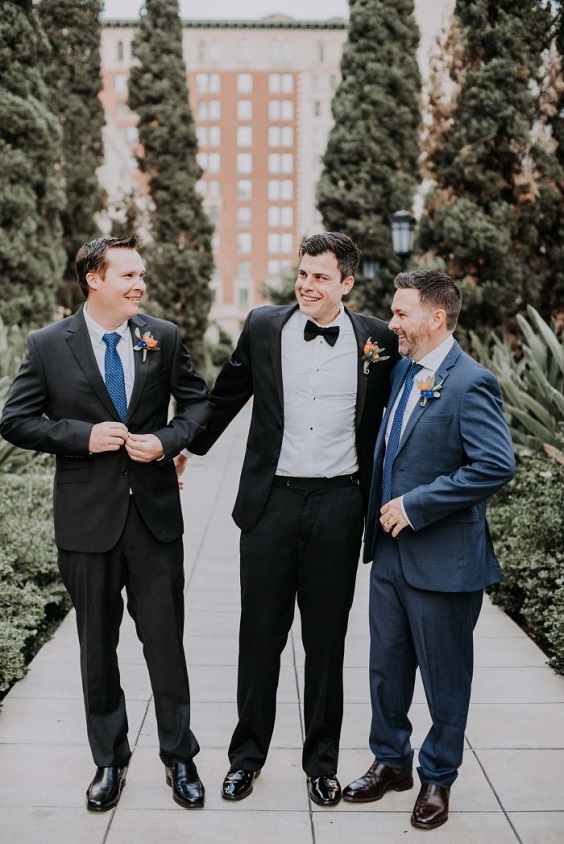 black groomsmen suits with orange boutonniere and royal blue ties for royal blue wedding colors 2024 royal blue and orange