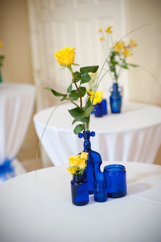 yellow flower in royal blue bottles and vases as wedding table décor for royal blue wedding colors 2024 royal blue and yellow