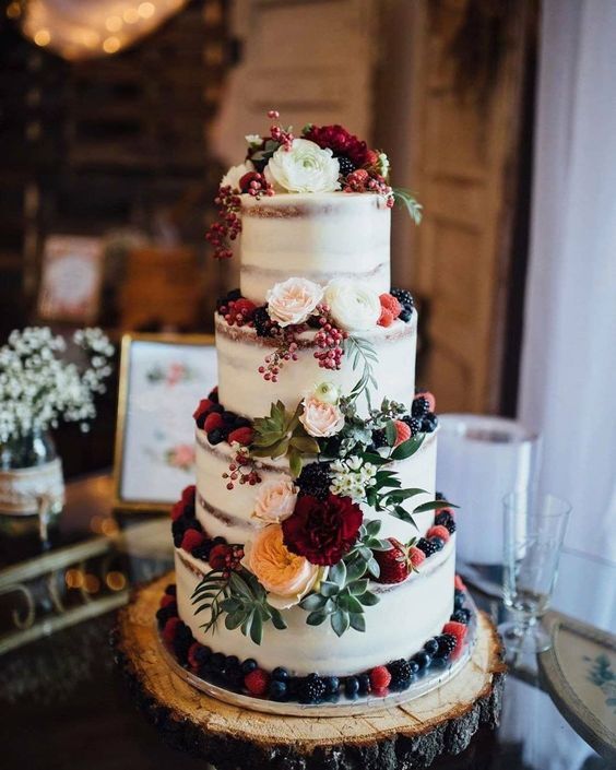 nude wedding cake dotted with burgundy flowers and blueberries for december wedding colors 2024 burgundy navy and green