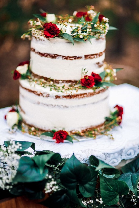 nude wedding cake dotted with red flowers and greenery for january wedding colors for 2024 emerald green and red