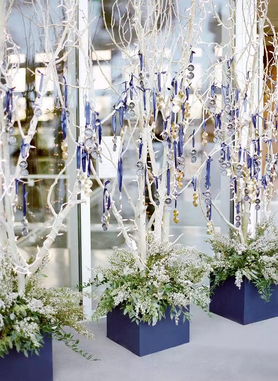 the escort card table featured branches hung with golden monogrammed compasses for january wedding colors for 2024 navy blue gold and white