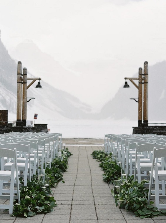 white wedding chairs decorated with greenery for january wedding colors for 2024 sage green and brown