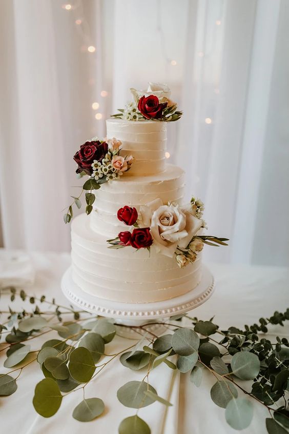 white wedding cake with burgundy red and pink flowers for july wedding colors combos for 2024 burgundy and ivory