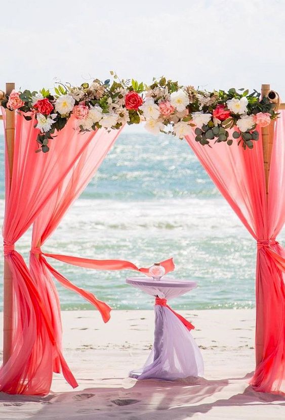 coral wedding arch with flowers and greenery for july wedding colors combos for 2024 coral and cream