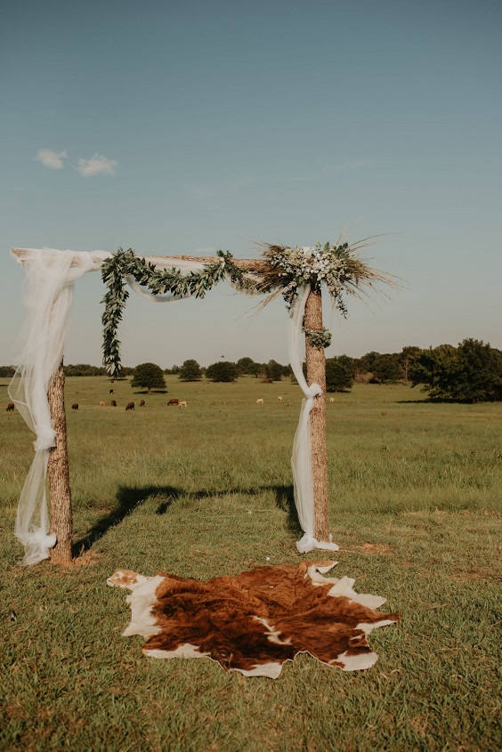 wooden wedding arch with white cloth and sage shade greenery for country wedding colors for 2025 sage green and white